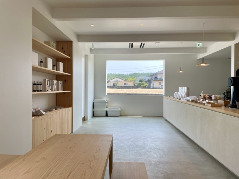 木製の棚やテーブルが置かれた白基調のカフェ店内