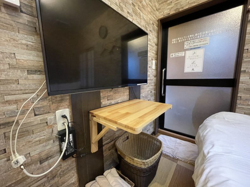壁掛けのテレビの下に開かれた、簡易的な折りたたみテーブル
