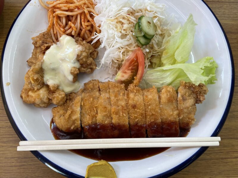 割り箸が丸皿に置いてあるトンカツとチキン南蛮定食