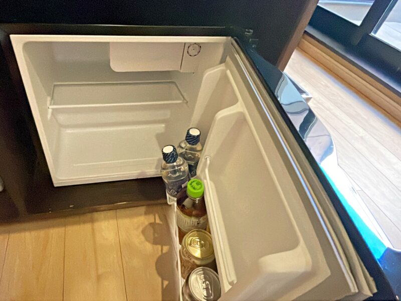 小型の冷蔵庫を開けた扉側に水とジュース